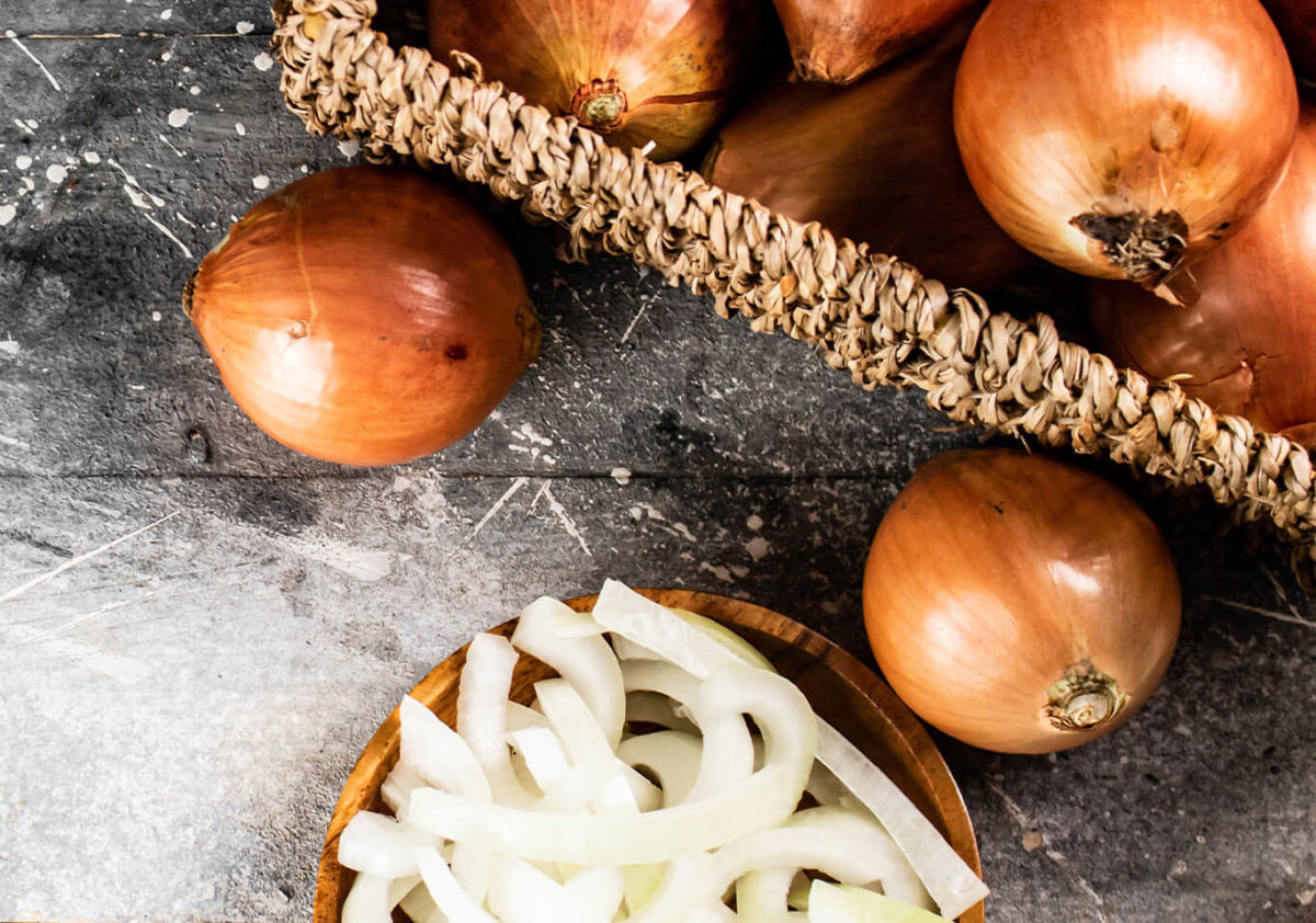 Whole Onions in a basket with chopped onions on the side. Cultured Onion Juice Powder Awareness Photo Cropped.